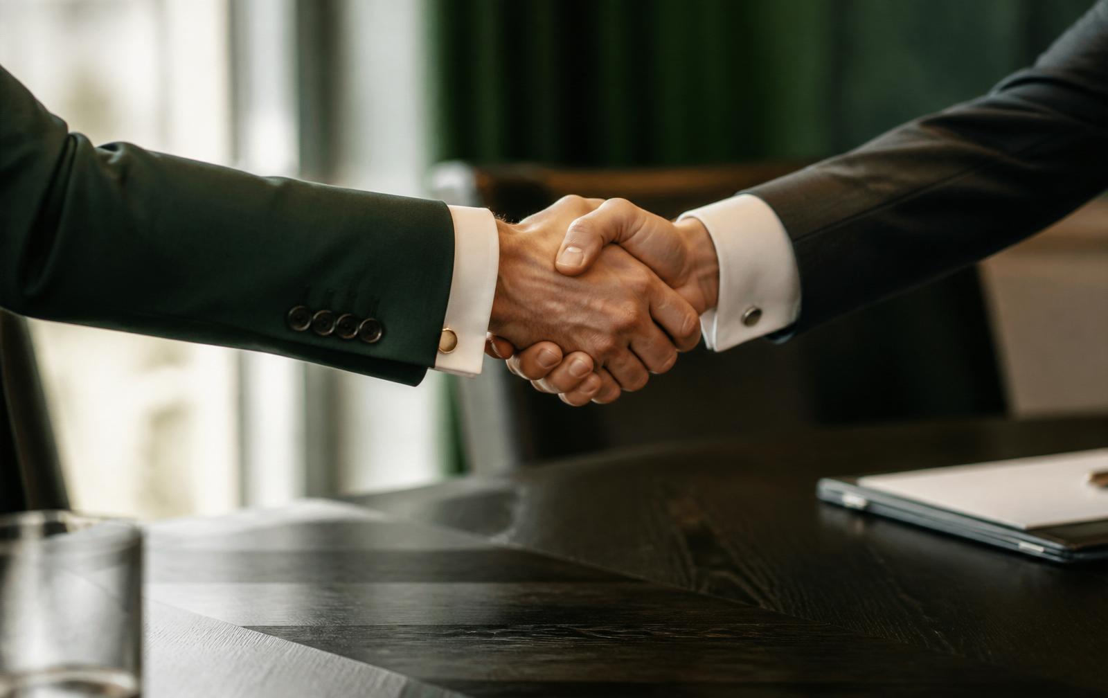 Handshake between two advisors at a dark conference table